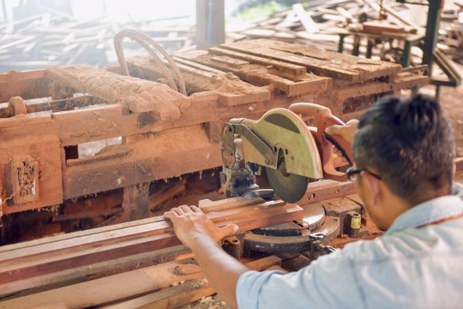 Carpenter cutting a plank of wood using a machine