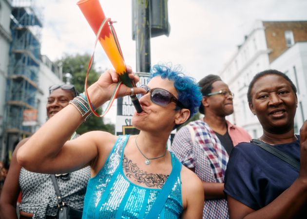 London, England, United Kingdom - August 28, 2022: Tattoeod woman blowing vuvuzela in street