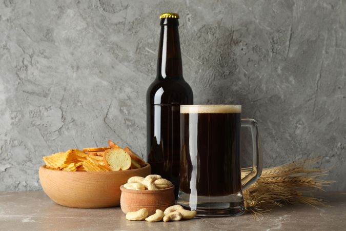 Beer, wheat and snacks on gray background