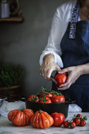 Woman cutting tomatoes in pot at table