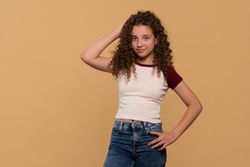 Young girl posing with hand on head, smiling confidently