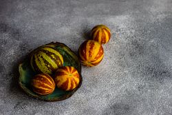 Organic mini melons on grey counter with space for text