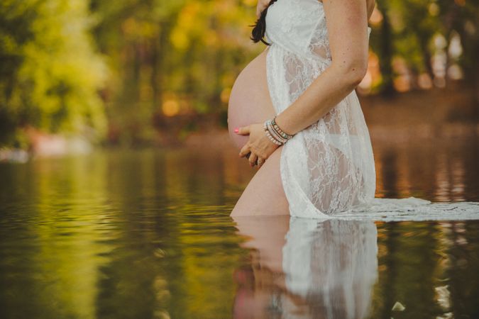 Pregnant woman standing in lake water