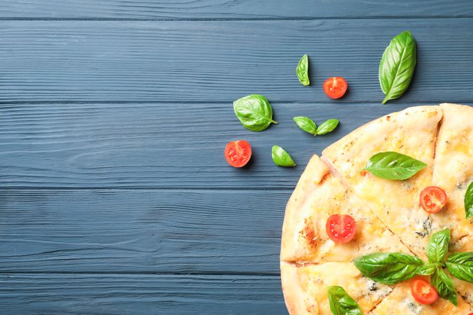 Cheese pizza with tomatoes and basil on wooden background, copy space