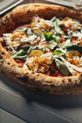 Two gourmet pizzas with toppings in delivery boxes on wooden table surface