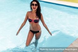 Portrait of happy young woman wearing bikini standing in pool 42N7d4