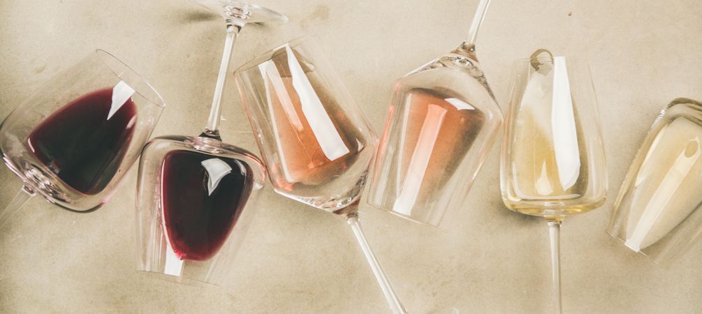 Glasses of wine laying on grey background, wide composition