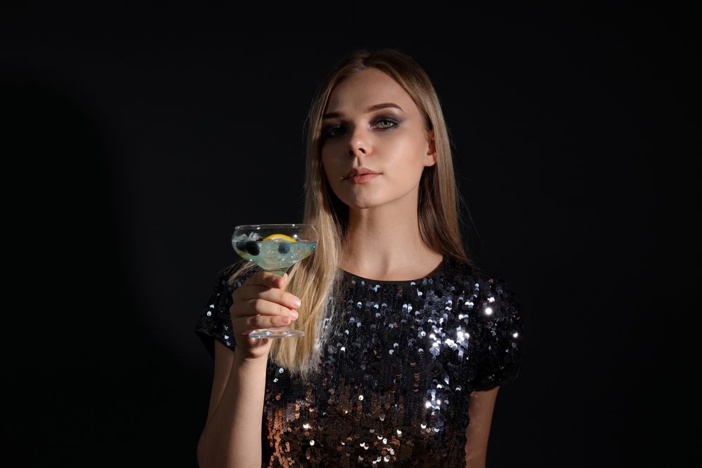 A woman at a party in the style of Halloween with a cocktail in her hands
