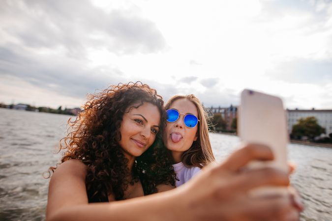 Two young women taking selfie with one sticking tongue out