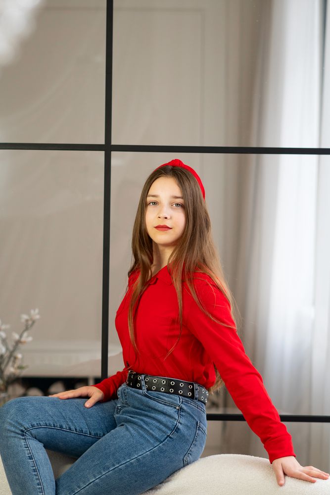 Portrait of teen girl sitting on sofa by window.