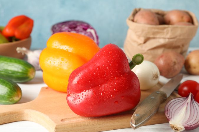 Vegetables, board and knife on wooden background, close up