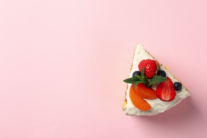 Piece of berry cream cake on pink background. Delicious dessert