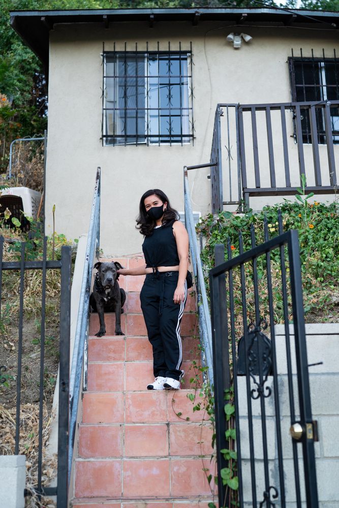 Woman standing on her front stairs in PPE mask about to take her dog on a walk