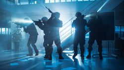 Masked Fireteam of Armed SWAT Police Officers Storm a Dark Seized Office Building with Desks and Computers.