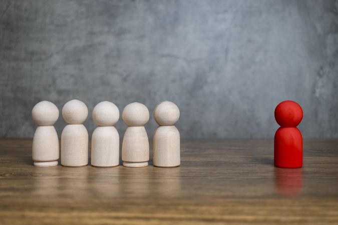 red wooden figure stand to the wooden group crowd. leadership and teamwork concept
