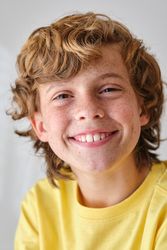 Smiling boy with brown hair on light background