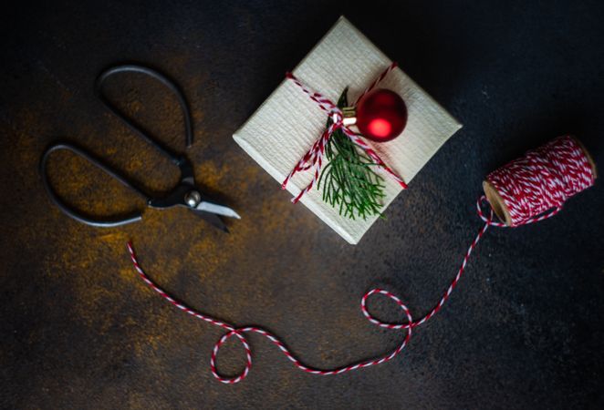 Top view of single Christmas gift with red string and scissors