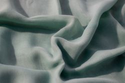 Nude green fabric wavy crumpled background texture with copy space.