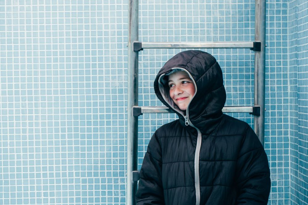 Boy in warm clothes standing in empty pool