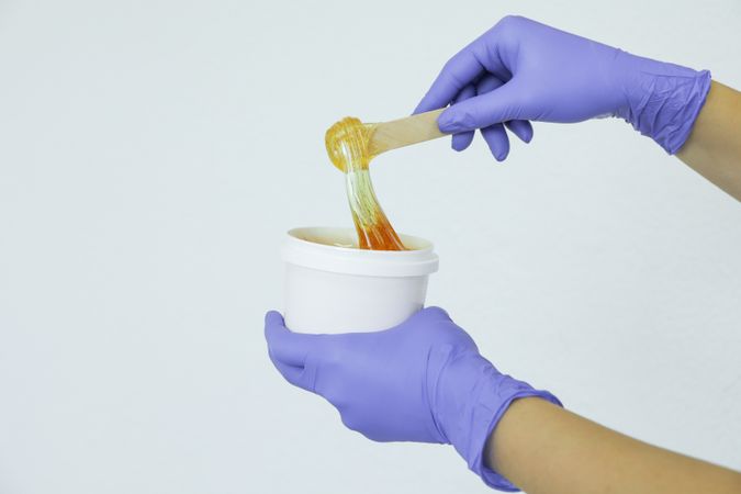 Women's hands holding liquid yellow paste for sugaring, copy space