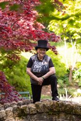 Woman in top hat with leg on bridge in green park