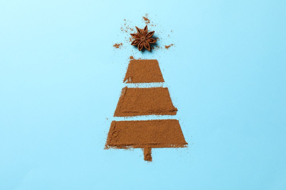 Christmas tree made of cinnamon powder on blue background, space for text