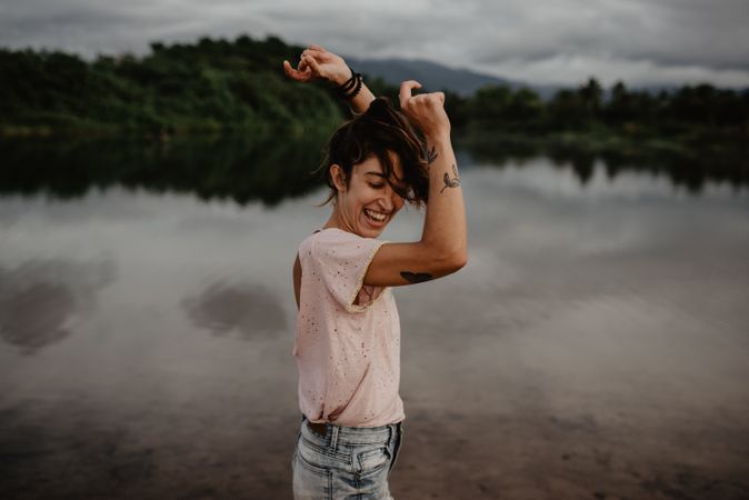 Cheerful woman dancing near lake