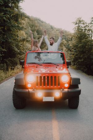 Loving couple sitting on car on road near forest