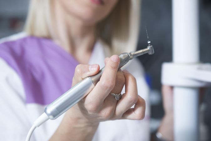 Close up of female dentist holding drill