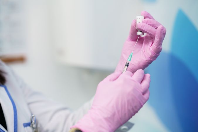 Female in latex gloves filling up syringe