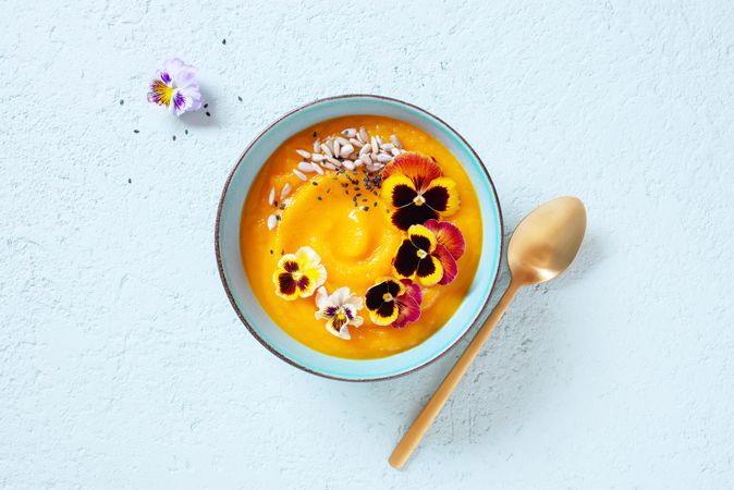 Top view of creamy pumpkin soup with edible flowers