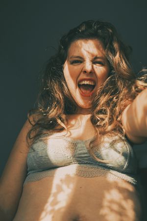 Portrait of smiling woman in gray bra with floral shadow from the window