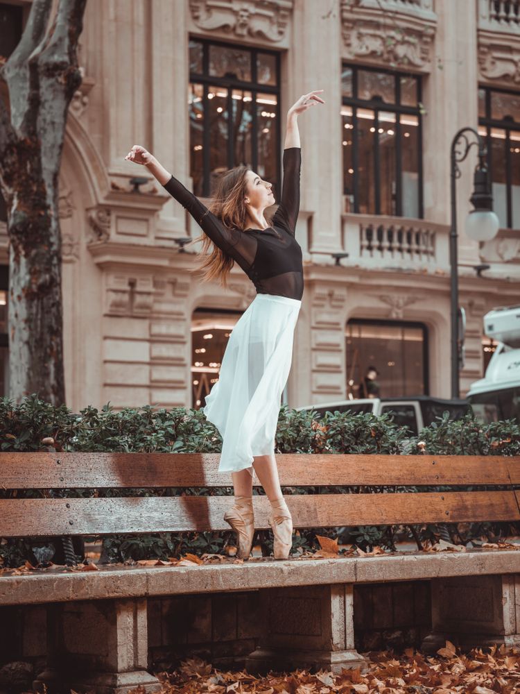 Gentle ballerina dancing on street bench