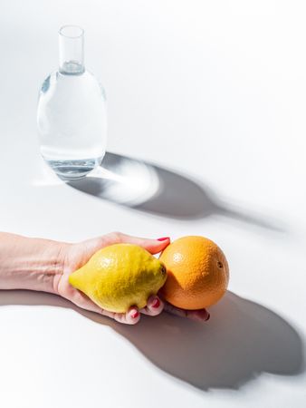 Composition of a hand with citrus and jar of water