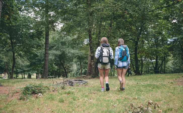 Two women friends with backpacks walking