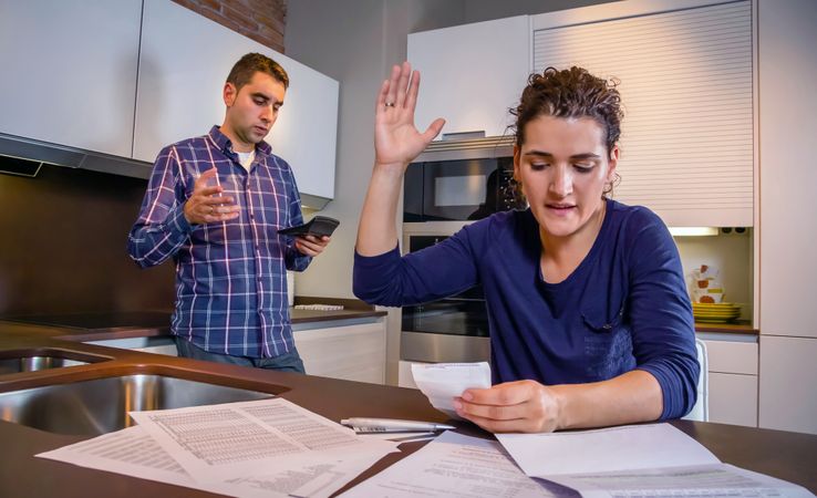 Frustrated couple discussing bills together in their kitchen