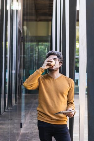Man drinking takeaway coffee and looking away