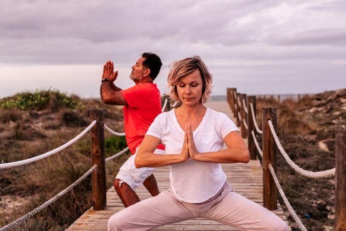 Adult couple meditating on wooden path