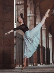 Flexible woman ballerina dancing in pointe shoes in arched passa