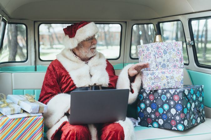 Santa Claus working at laptop in van