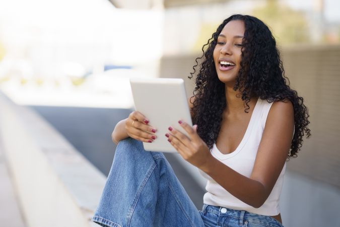 A Young Woman Happily Enjoying Using Her Tablet While Relaxing Outdoors Surrounded by Nature