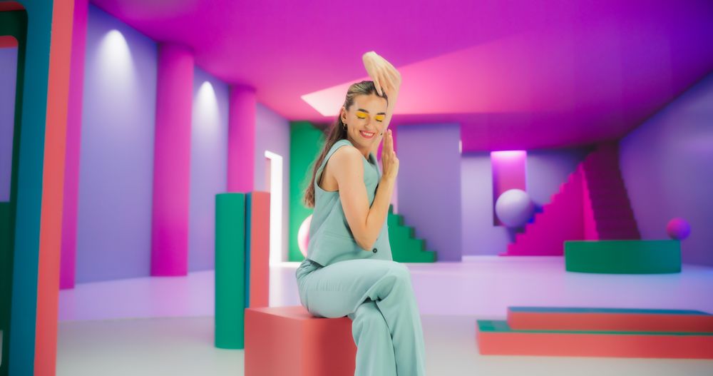 Woman with Bright Makeup Dancing Energetically and Interacting with Colorful Geometric Abstract Environment. Creative Young Female Happily Performing Dance with Hand Movement
