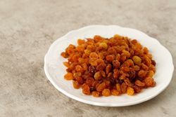 Ceramic bowl of golden raisins on marble table