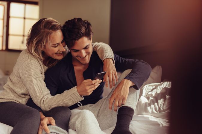 Cheerful man and woman looking at cell phone together