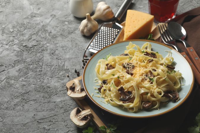 Composition with plate of tasty pasta and ingredients for cooking on gray background