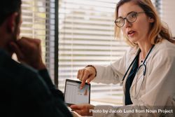 Confident female doctor talking with patient with test results on tablet 5XP775