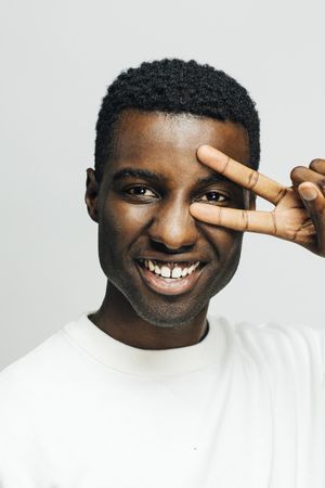 Close up portrait happy Black man in a bright room making a peace sign