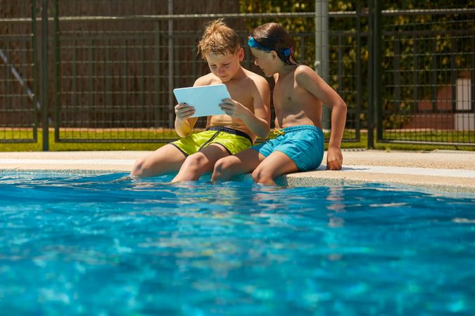 Boys on poolside browsing tablet