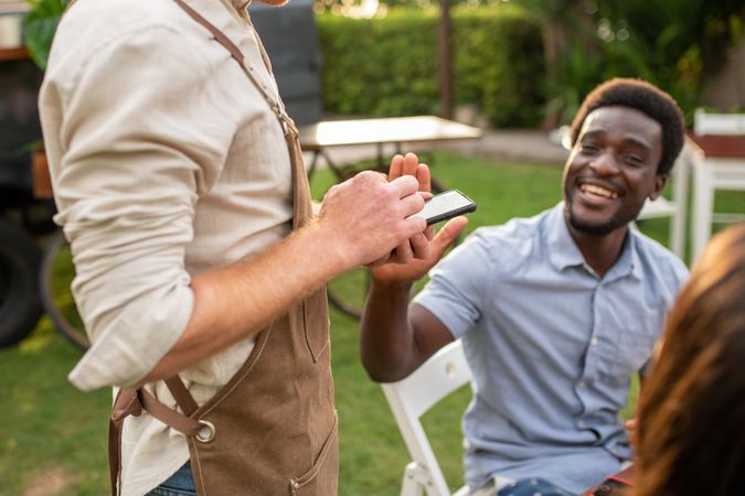 Cheerful Black man using smartphone in park