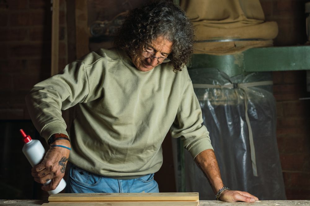 Carpenter gluing wooden board in workshop